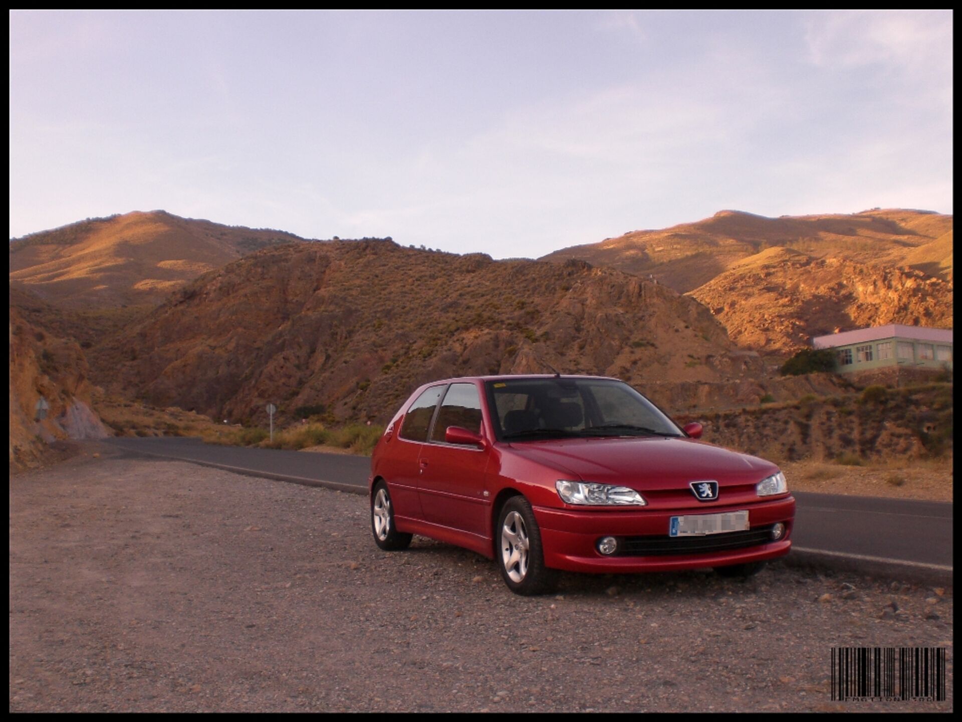 Peugeot 306 rojo en las montañas al atardecer